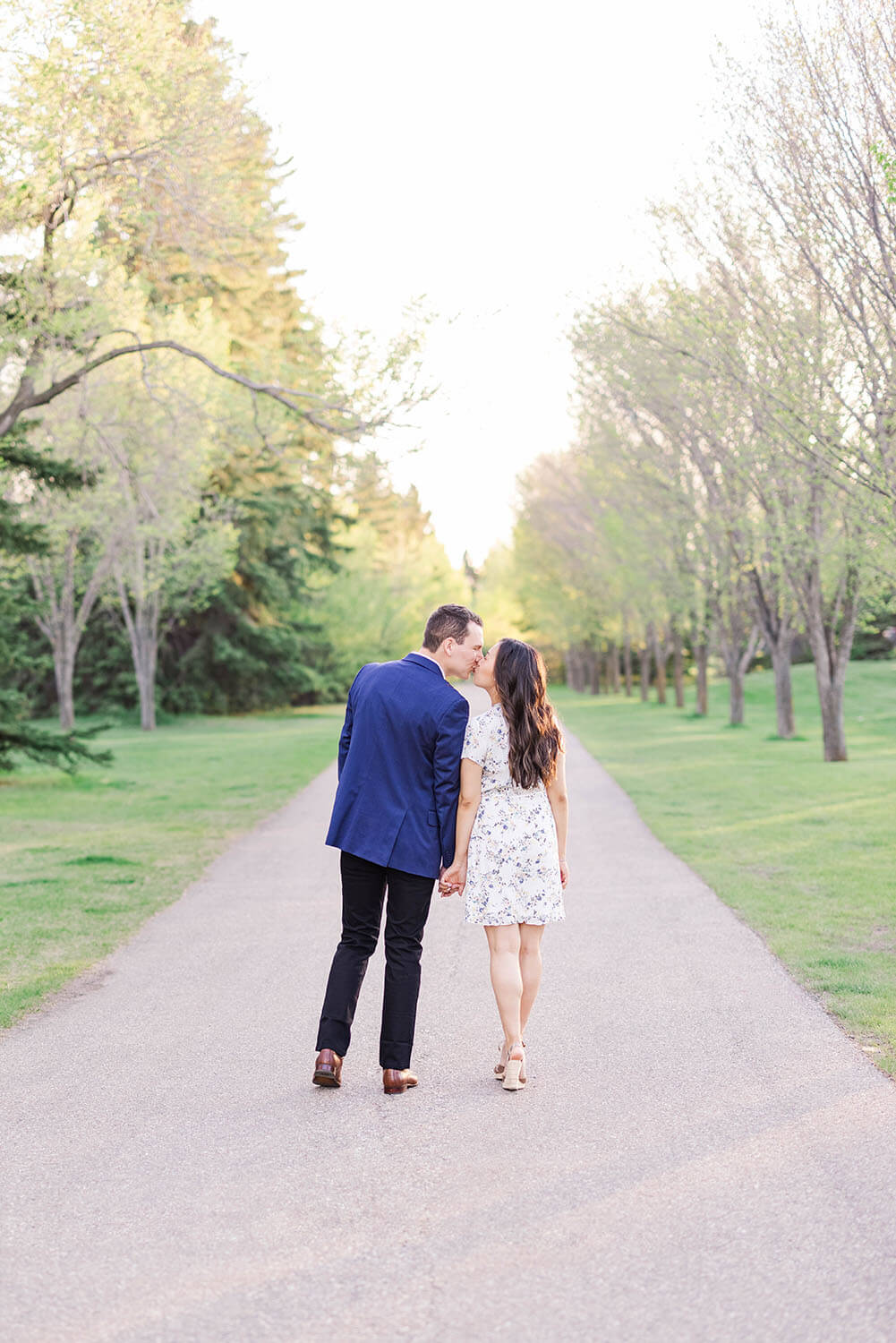 an asian female leaning in for a kiss with her native canadian lover walking down a path with autumn leaves either side