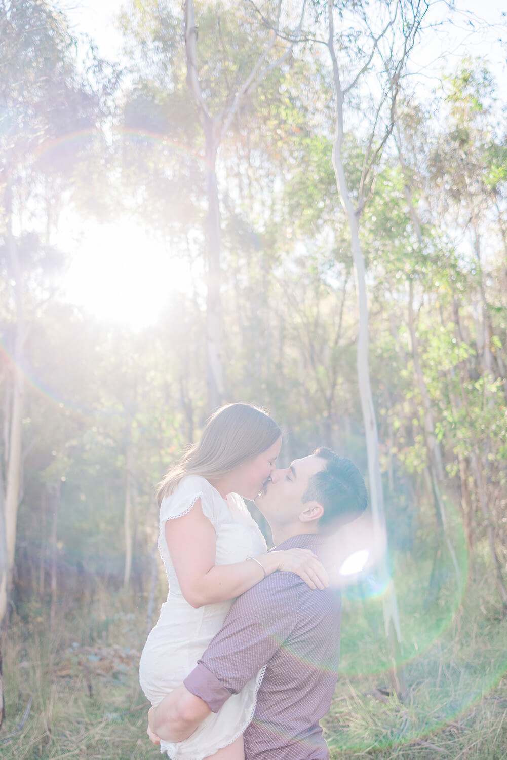 man lifts woman into the light and gives her a kiss