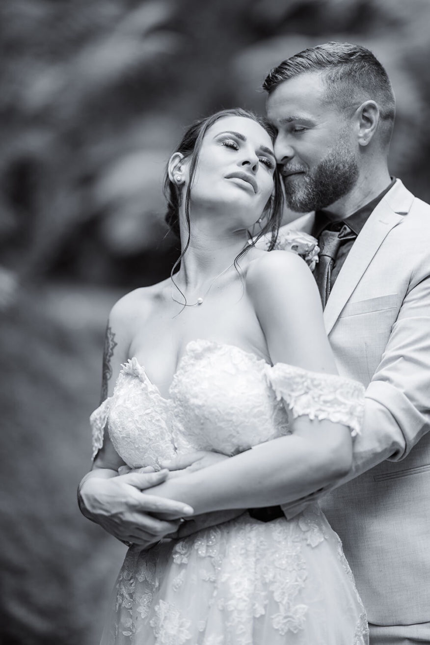 groom-hugging-new-wife-from-behind-as-she-looks-up