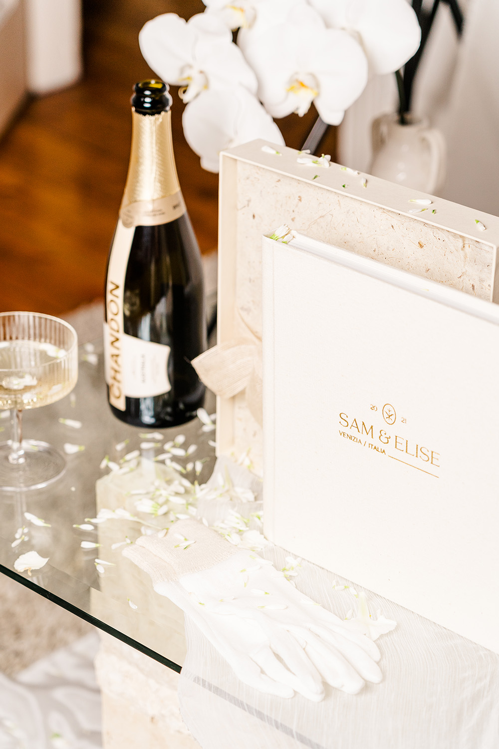 a wedding album on a table next to a bottle of wine and glass