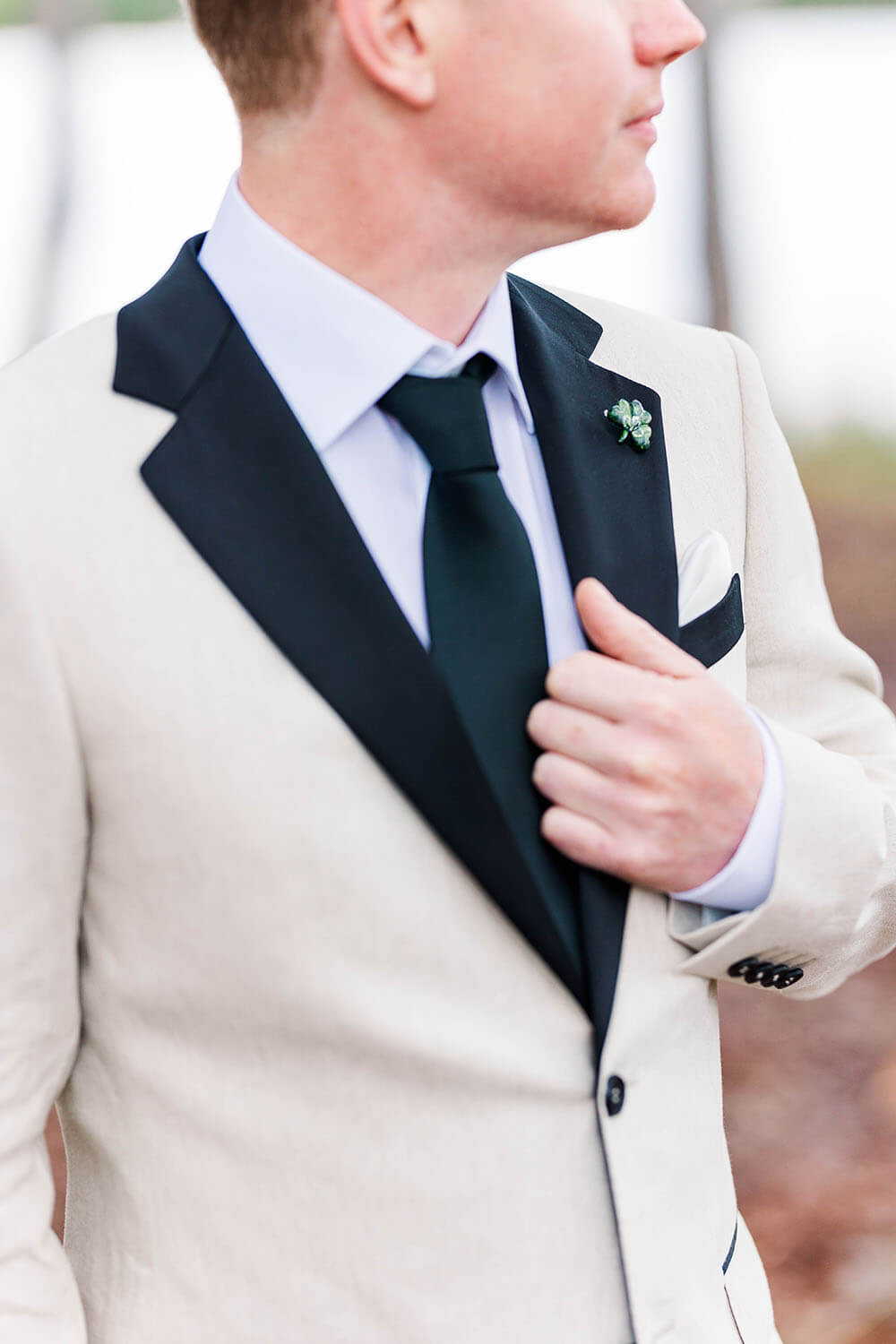 A groom with white suit jacket with black collar.