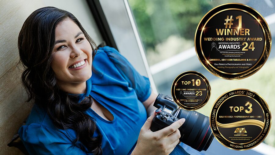 a dark haired female photographer holding her camera with award logos next to her
