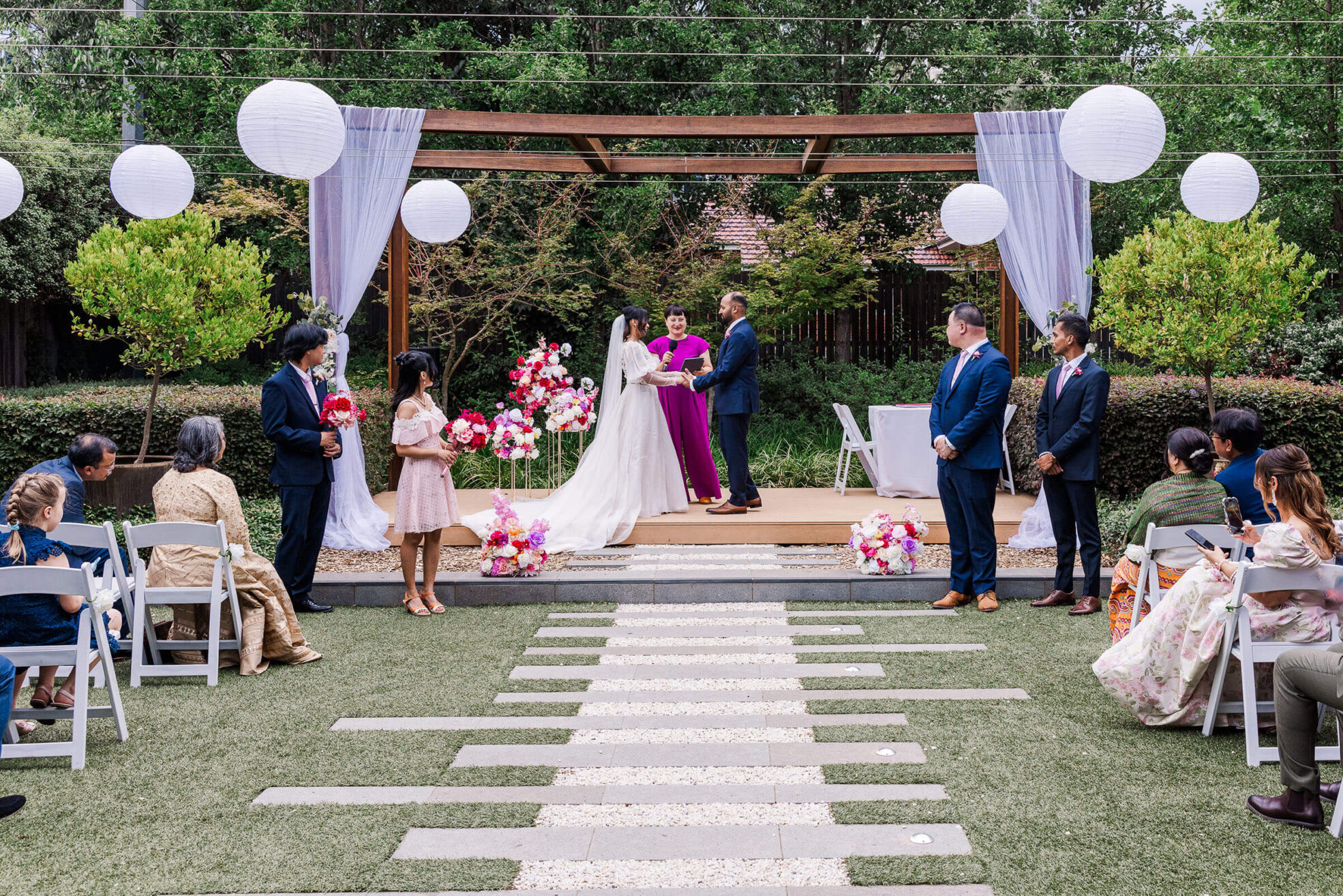 Bride and Groom facing each other making vows in front of a celebrant in a purple jumpsuit